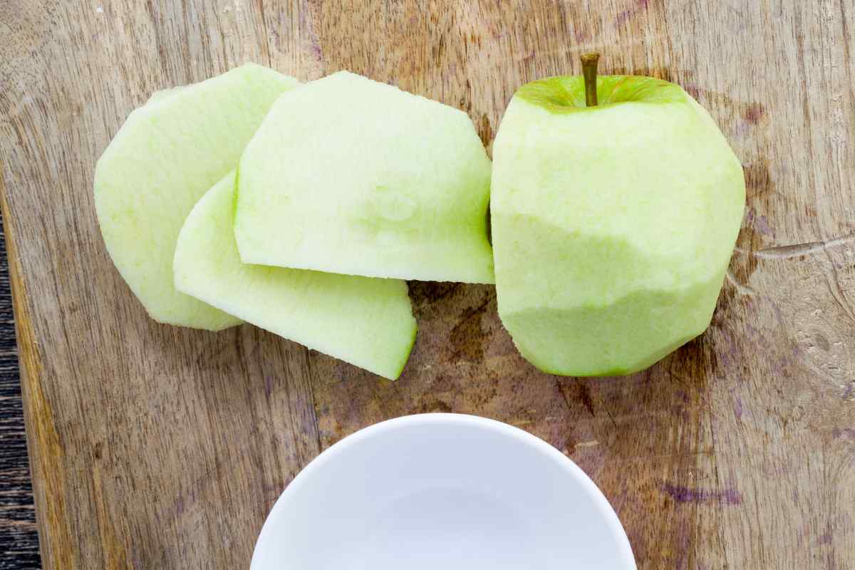 Image of some half sliced peeled apple pieces on a wooden board, this is part of a blog about making apple crumble with kids