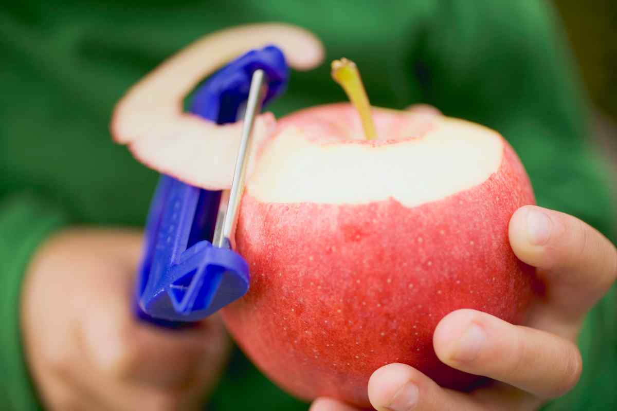 Image of an apple being peeled with a blue plastic peeler, this is part of a blog about making apple crumble with kids