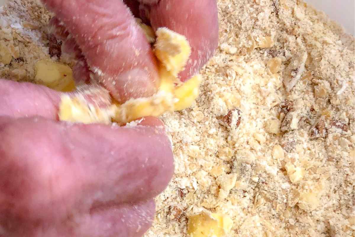 Image of two hands rubbing butter sugar and flour together, this is part of a blog about making apple crumble with kids
