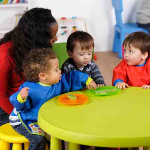 Descriptive image for a quiz multiple choice question, image shows a home educator or childminder supervising some kids at snacktime