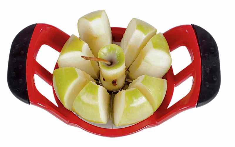 Image of a combined apple slicer and corer, the kind that you press down over a whole apple to separate into segments with the core taken out of the middle. This one is red with black handles and has a sliced apple in the middle to show how it has worked