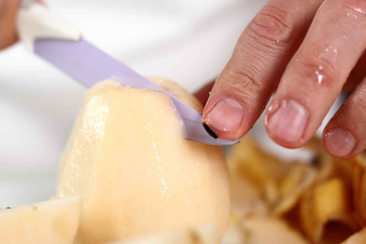 Image of a hand slicing a very soft peeled pear, this is part of a blog about making pear and coconut milkshake with kids