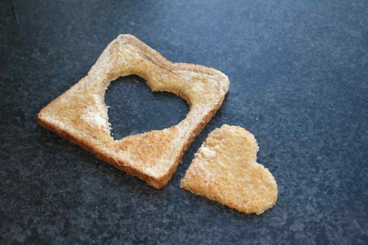 Picture of some toast with a heart shaped hole cut out of it and the cut out part beside it, as part of a blog about a Valentine's recipe for kids to make independently called Love Toast.