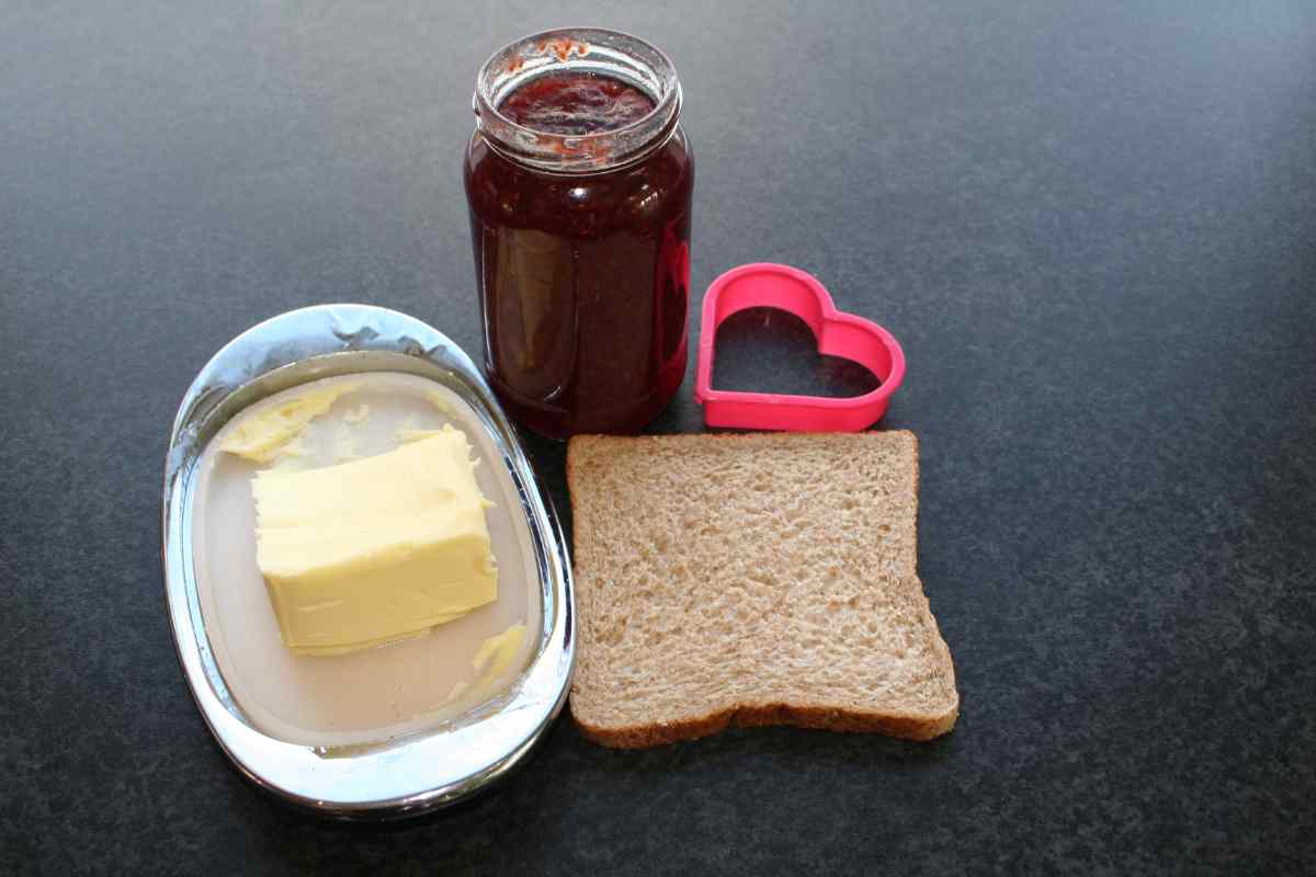 Picture of some ingredients for a recipe, some jam, bread, butter and a cookie cutter, as part of a blog about a Valentine's recipe for kids to make independently called Love Toast.