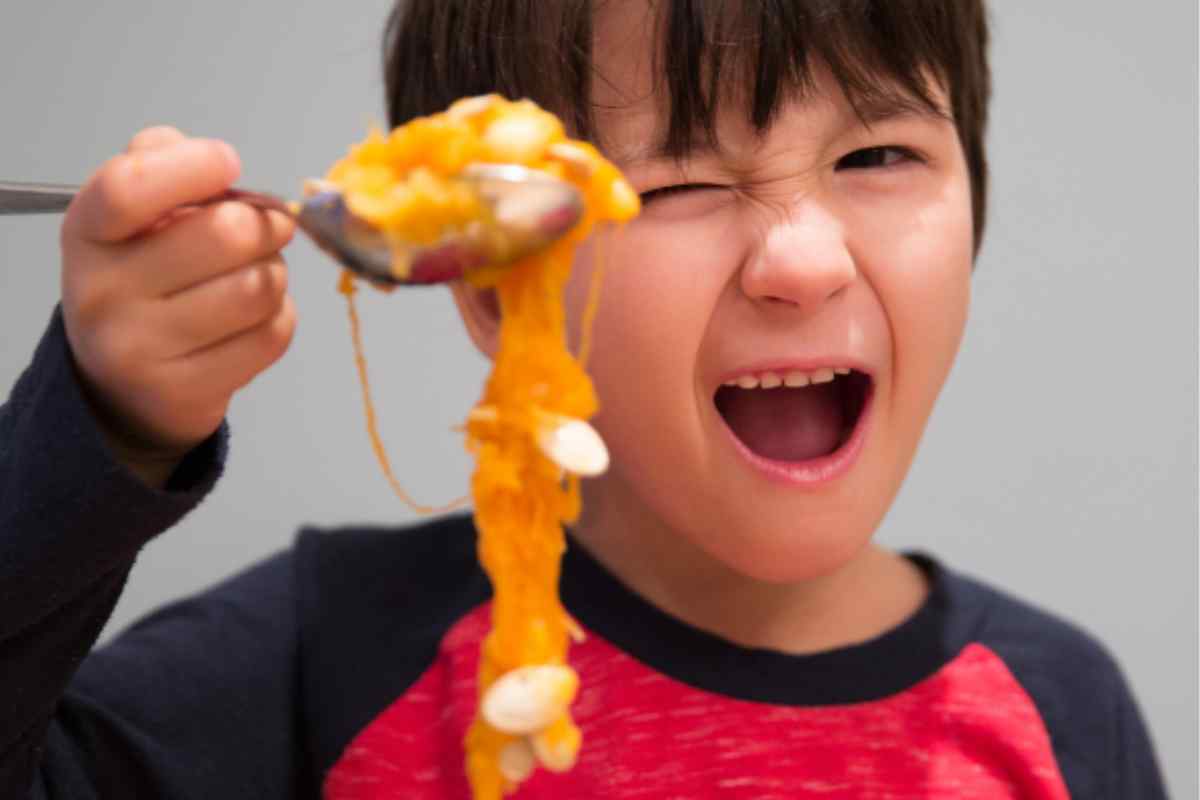 Image of a child holding up a forkful of gooey pumpkin flesh and seeds with an awestruck expression as part of a blog about what to do with your pumpkin seeds with kids