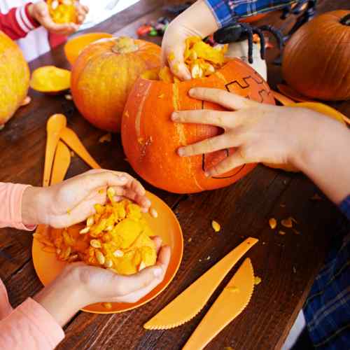 An image of kids pulling seeds from a pumpkin, as a header thumbnail for a blog about what to do with your pumpkin seeds